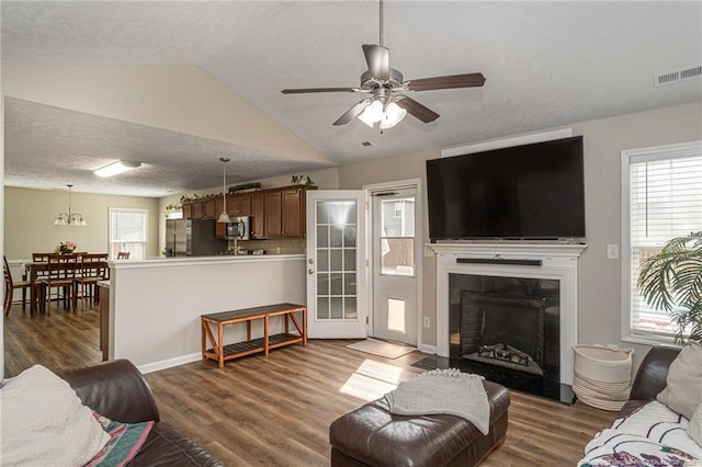 living room featuring lofted ceiling, a fireplace, visible vents, and dark wood finished floors