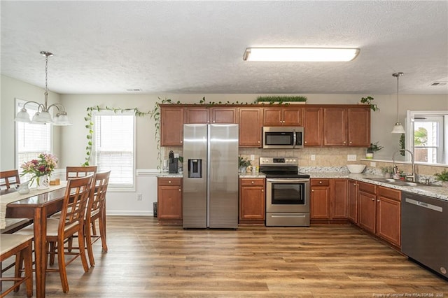 kitchen featuring stainless steel appliances, brown cabinetry, a sink, and tasteful backsplash