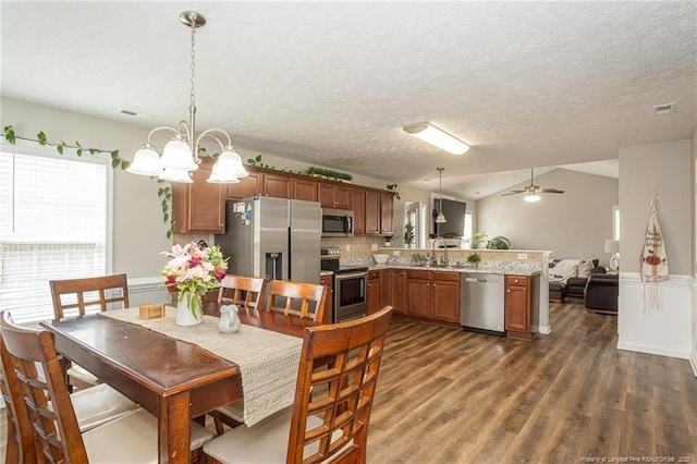 dining space with lofted ceiling, dark wood-style floors, a textured ceiling, and ceiling fan with notable chandelier