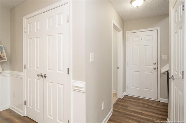 hall with baseboards, dark wood-type flooring, and a textured ceiling