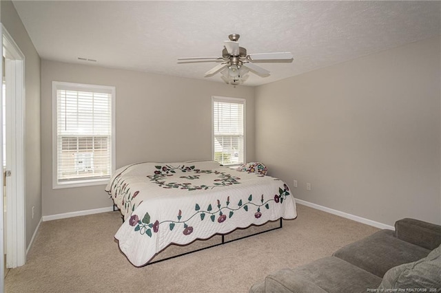 carpeted bedroom with visible vents, baseboards, ceiling fan, and a textured ceiling