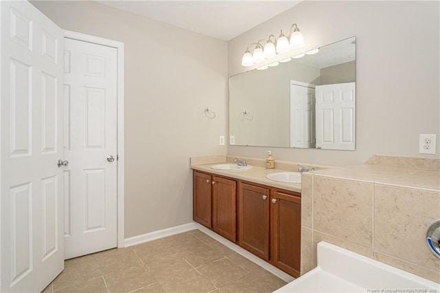 bathroom featuring double vanity, baseboards, a sink, and tile patterned floors