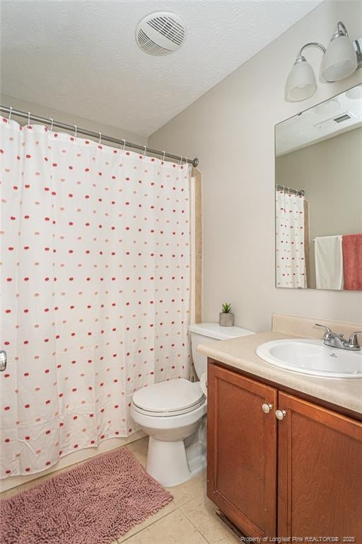 bathroom with visible vents, toilet, vanity, a textured ceiling, and tile patterned flooring