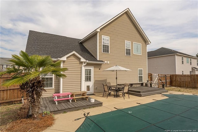 rear view of house featuring a fenced in pool, a fenced backyard, a shingled roof, and a wooden deck