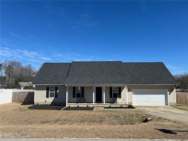 ranch-style house featuring a shingled roof, concrete driveway, an attached garage, covered porch, and fence