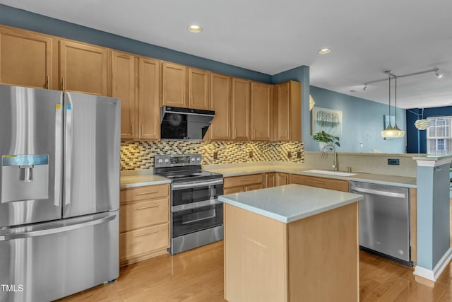 kitchen featuring appliances with stainless steel finishes, light countertops, a sink, and a peninsula