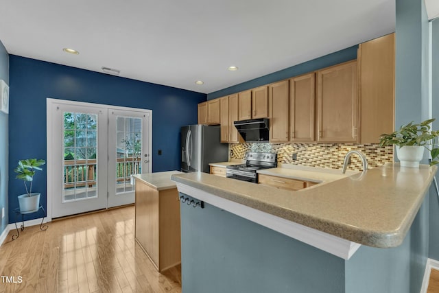 kitchen featuring stainless steel appliances, light countertops, backsplash, light wood-type flooring, and a peninsula