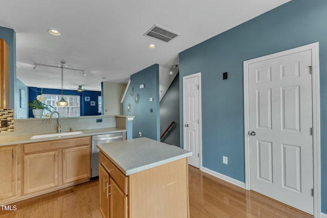 kitchen with light countertops, visible vents, stainless steel dishwasher, a sink, and light wood-type flooring