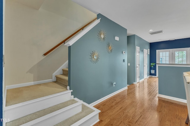 staircase featuring wood finished floors, visible vents, and baseboards