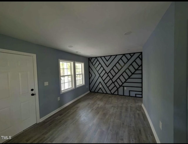 unfurnished living room featuring wood finished floors and baseboards