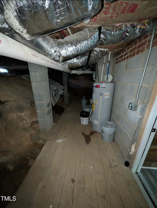 below grade area featuring concrete block wall, wood-type flooring, and water heater