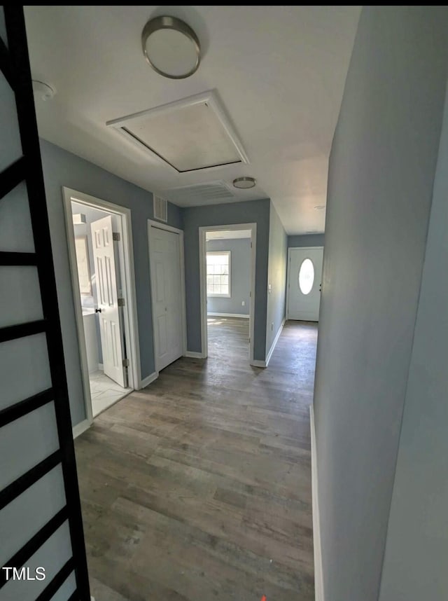 corridor featuring attic access, baseboards, and wood finished floors