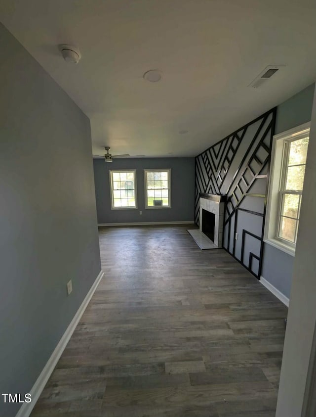 unfurnished living room with visible vents, a fireplace, baseboards, and wood finished floors