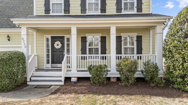 view of exterior entry featuring a shingled roof and a porch