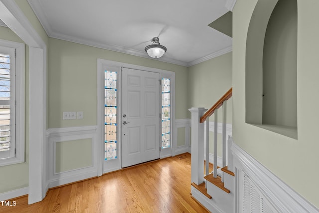 entryway featuring ornamental molding, a wealth of natural light, and stairs