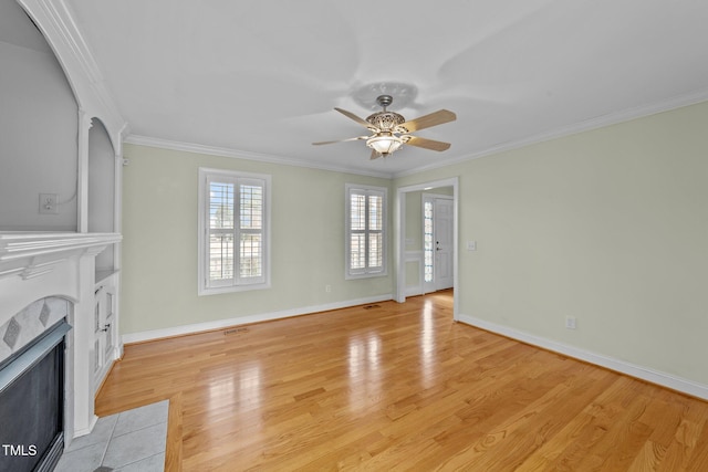 unfurnished living room with ornamental molding, baseboards, a fireplace, and light wood finished floors