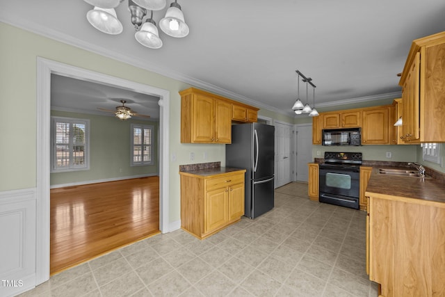 kitchen featuring black appliances, dark countertops, a sink, and crown molding