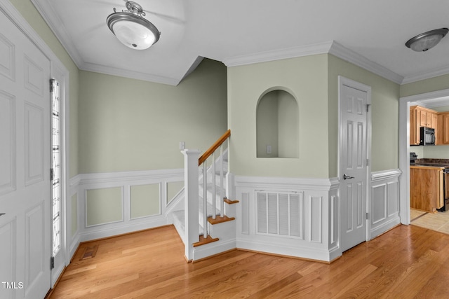 entryway featuring visible vents, stairway, light wood-style flooring, ornamental molding, and a healthy amount of sunlight