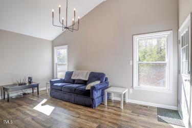 living room with high vaulted ceiling, wood finished floors, a wealth of natural light, and baseboards