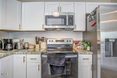 kitchen with appliances with stainless steel finishes, white cabinets, and light stone counters