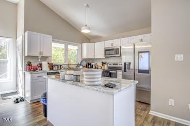 kitchen featuring stainless steel appliances, dark wood-type flooring, white cabinets, vaulted ceiling, and a center island