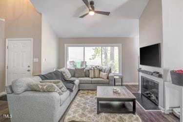 living room featuring lofted ceiling, ceiling fan, baseboards, and dark wood-style flooring