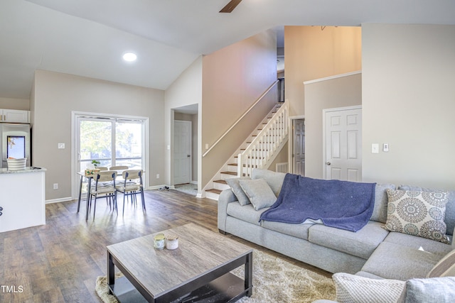 living area featuring stairway, a ceiling fan, wood finished floors, high vaulted ceiling, and baseboards