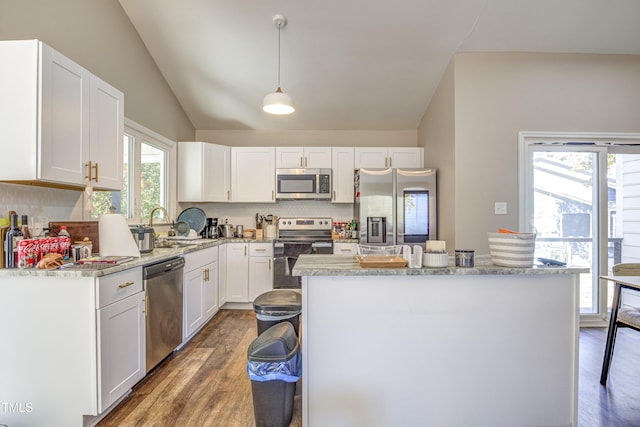 kitchen with vaulted ceiling, appliances with stainless steel finishes, white cabinets, and wood finished floors