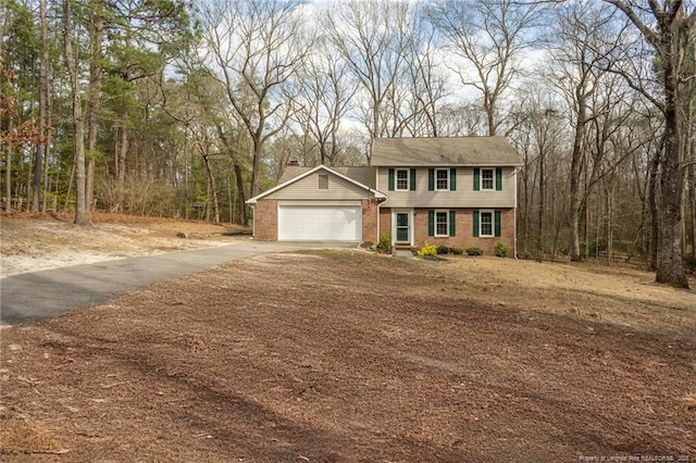 colonial inspired home with brick siding, driveway, and an attached garage