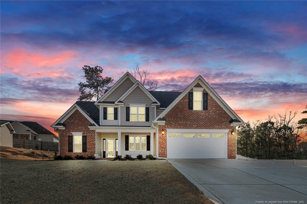 view of front of property featuring brick siding, an attached garage, a front yard, fence, and driveway