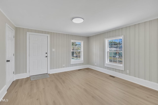 foyer with light wood-style floors, visible vents, and baseboards