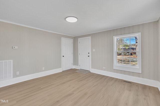 empty room with light wood-style floors, visible vents, and baseboards