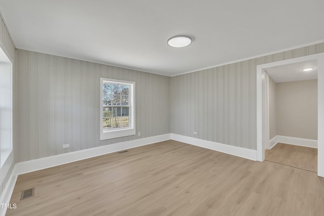 unfurnished room featuring light wood finished floors, visible vents, and baseboards