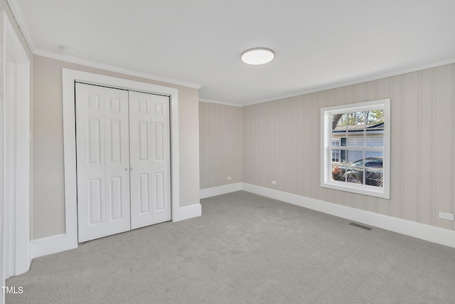 unfurnished bedroom featuring carpet, a closet, visible vents, and crown molding