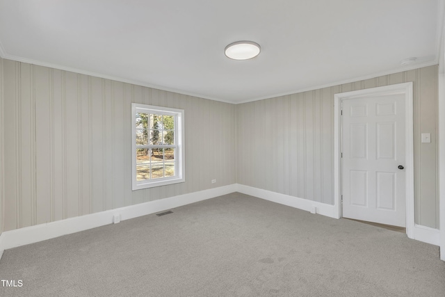 carpeted spare room with baseboards, visible vents, and crown molding