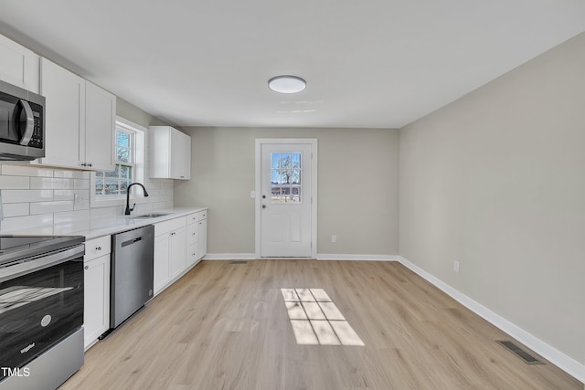 kitchen featuring stainless steel appliances, a sink, visible vents, light countertops, and decorative backsplash