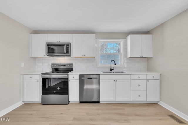 kitchen with stainless steel appliances, a sink, visible vents, and decorative backsplash