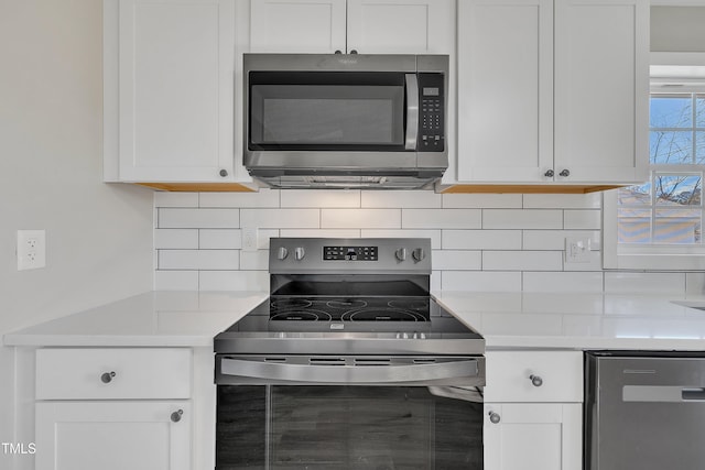 kitchen featuring white cabinets, decorative backsplash, stainless steel appliances, and light countertops