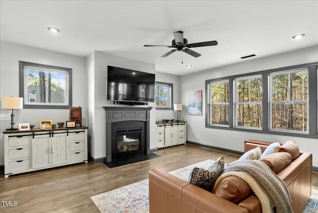 living room with a fireplace with flush hearth, baseboards, wood finished floors, and recessed lighting