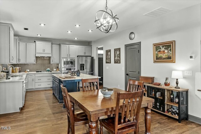 dining area with a notable chandelier, visible vents, wood finished floors, and recessed lighting