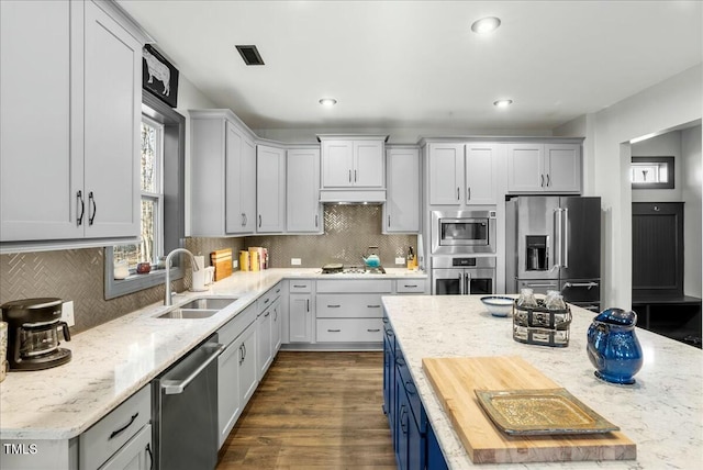 kitchen featuring light stone counters, dark wood-style flooring, visible vents, appliances with stainless steel finishes, and a sink