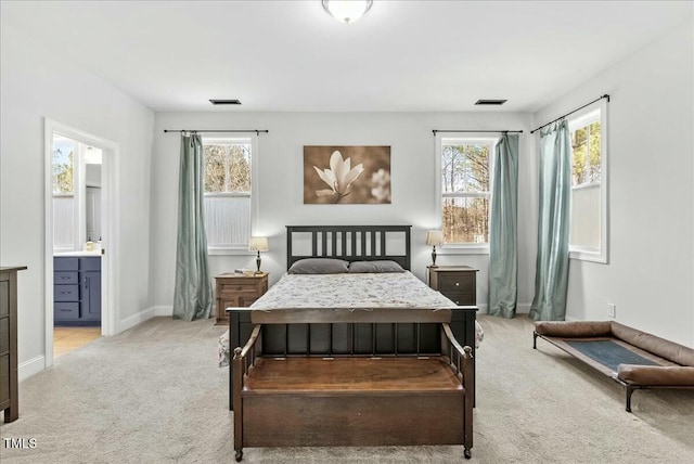 bedroom featuring light carpet, baseboards, visible vents, and ensuite bathroom