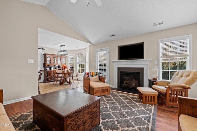 living area featuring visible vents, vaulted ceiling, and wood finished floors