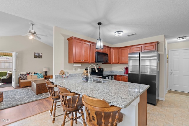 kitchen with visible vents, freestanding refrigerator, range with electric cooktop, black microwave, and a peninsula