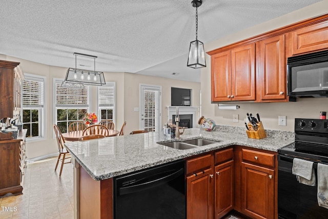 kitchen featuring light stone counters, hanging light fixtures, a sink, a peninsula, and black appliances