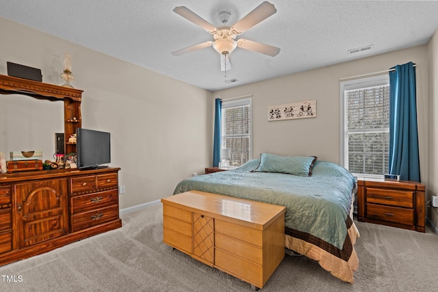 bedroom featuring a textured ceiling, visible vents, baseboards, a ceiling fan, and carpet