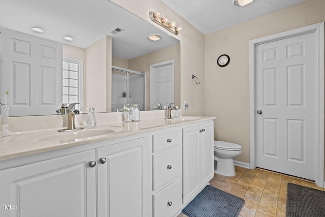 full bath with double vanity, a stall shower, a sink, and visible vents