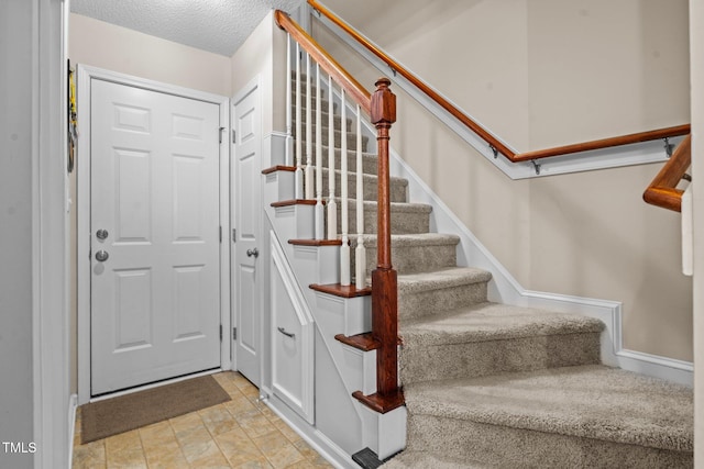 stairway with a textured ceiling and baseboards