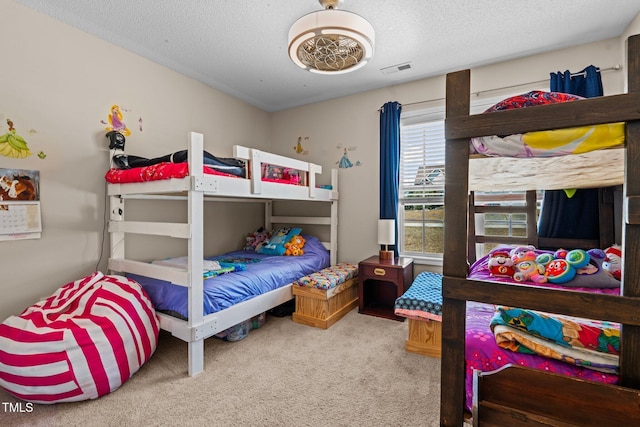 carpeted bedroom featuring a textured ceiling and visible vents