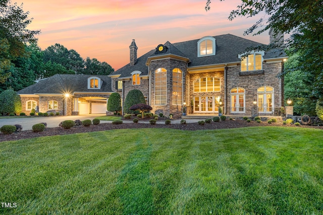 french country home featuring a garage, concrete driveway, french doors, a chimney, and a front yard